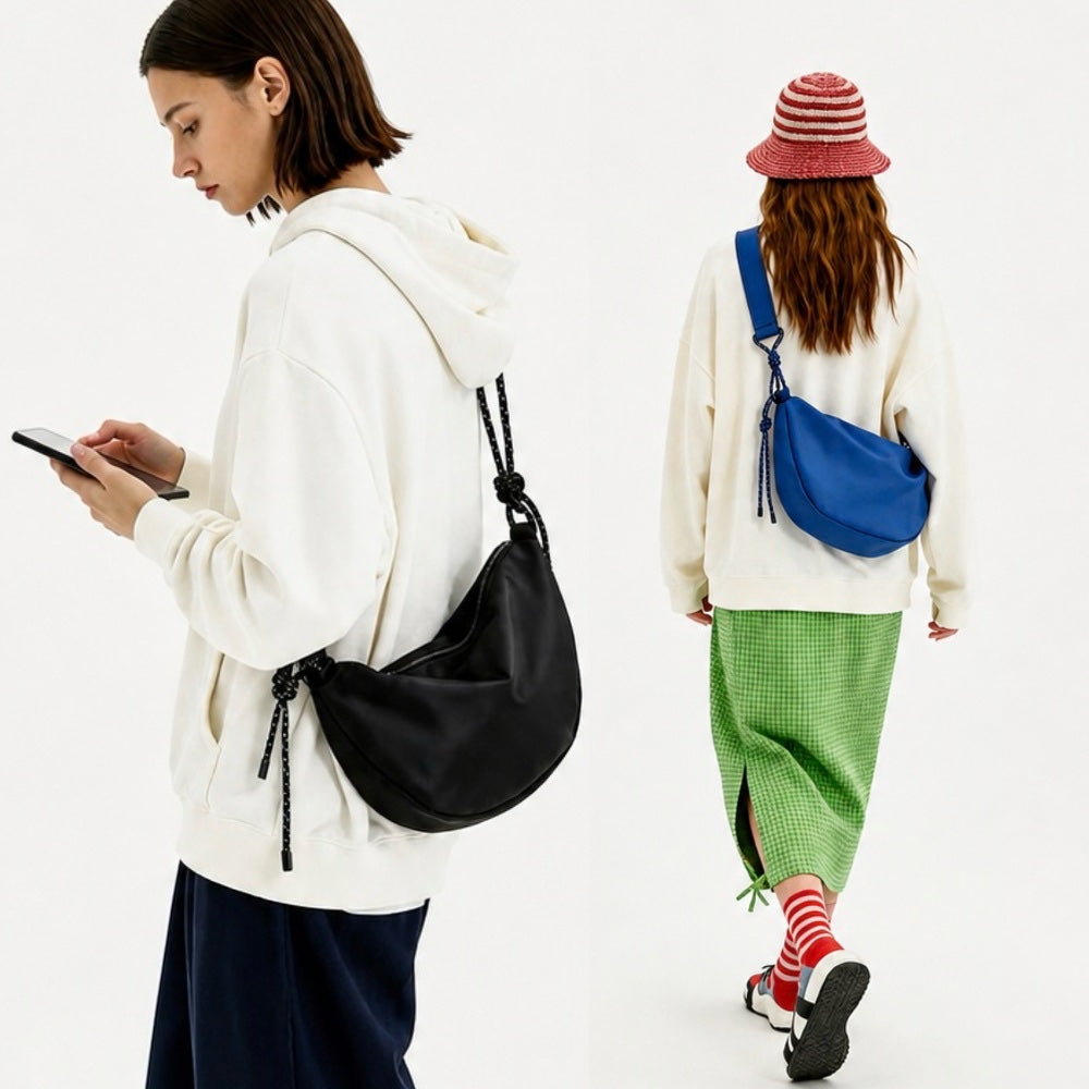 Two models wearing black and cobalt blue knotted crescent bags, showcasing the urban utility aesthetic.