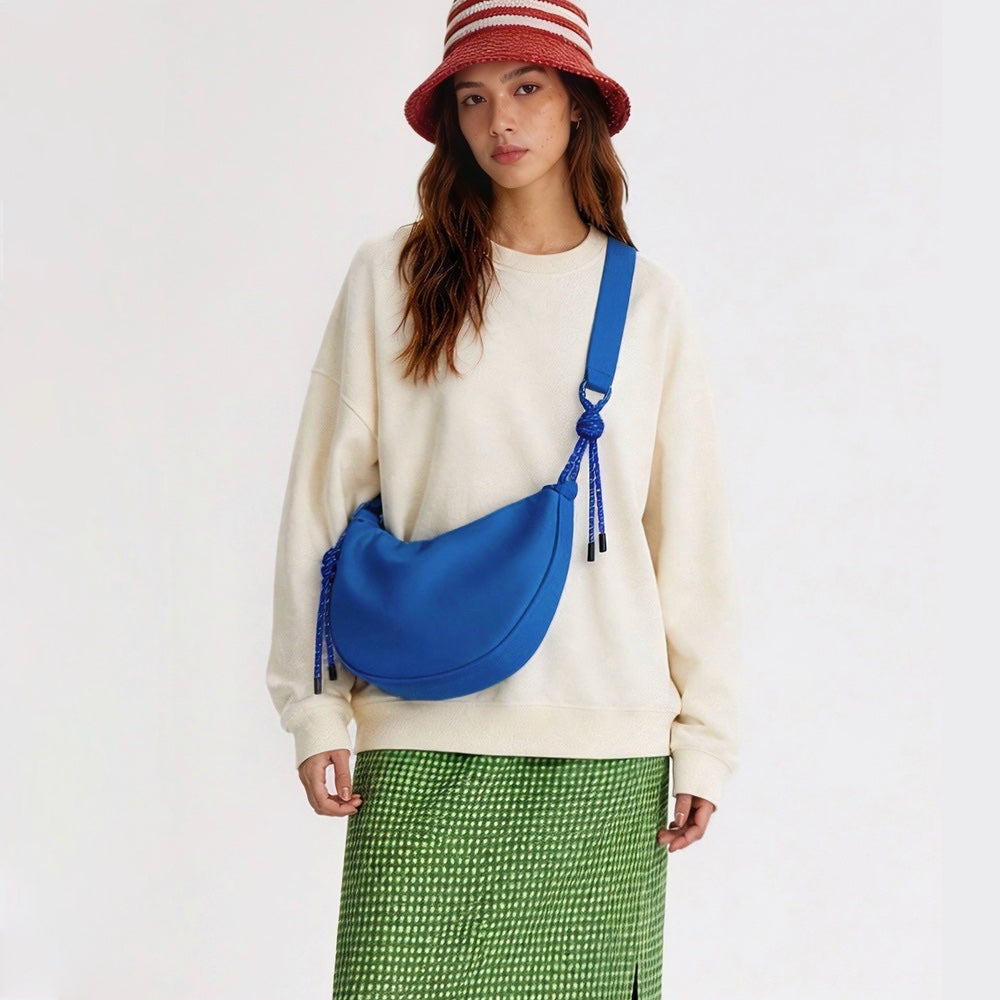 Model wearing a vibrant blue crescent bag, trendy water-resistant crossbody for iPad and essentials.