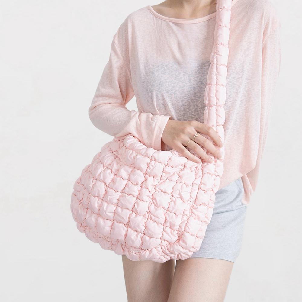 Model wearing the soft pink puffy crossbody bag with a light top.