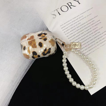 Flat lay of Leopard Print AirPods Case Cover with pearl string, great for daily protection and travel.