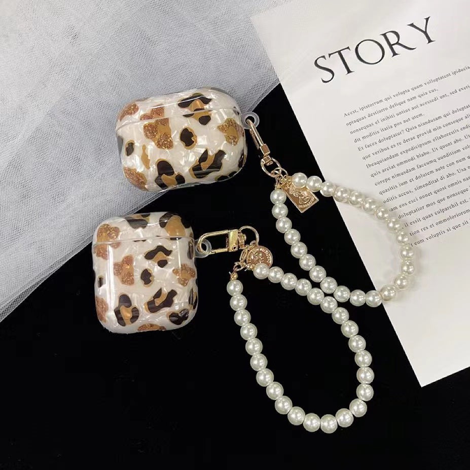 Two sizes of Leopard print silicone AirPods cases with pearl wrist strap and gold charms.
