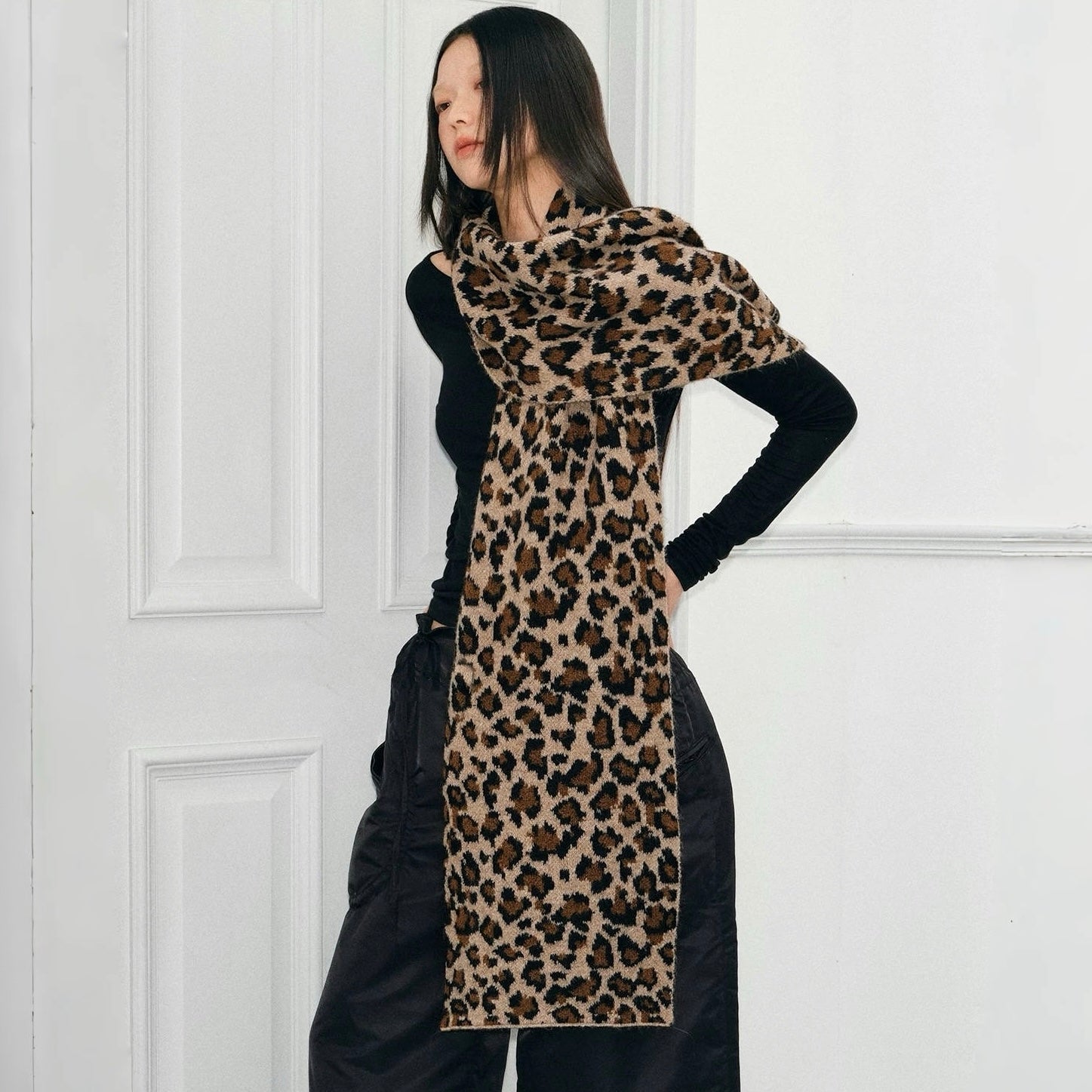 Model wearing long, wool blend leopard print knit scarf in brown and black, great for office layering and commuting.