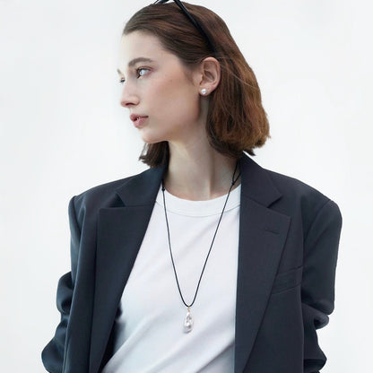 Flat lay of silver teardrop pendant necklace on white fabric, polished jewelry view