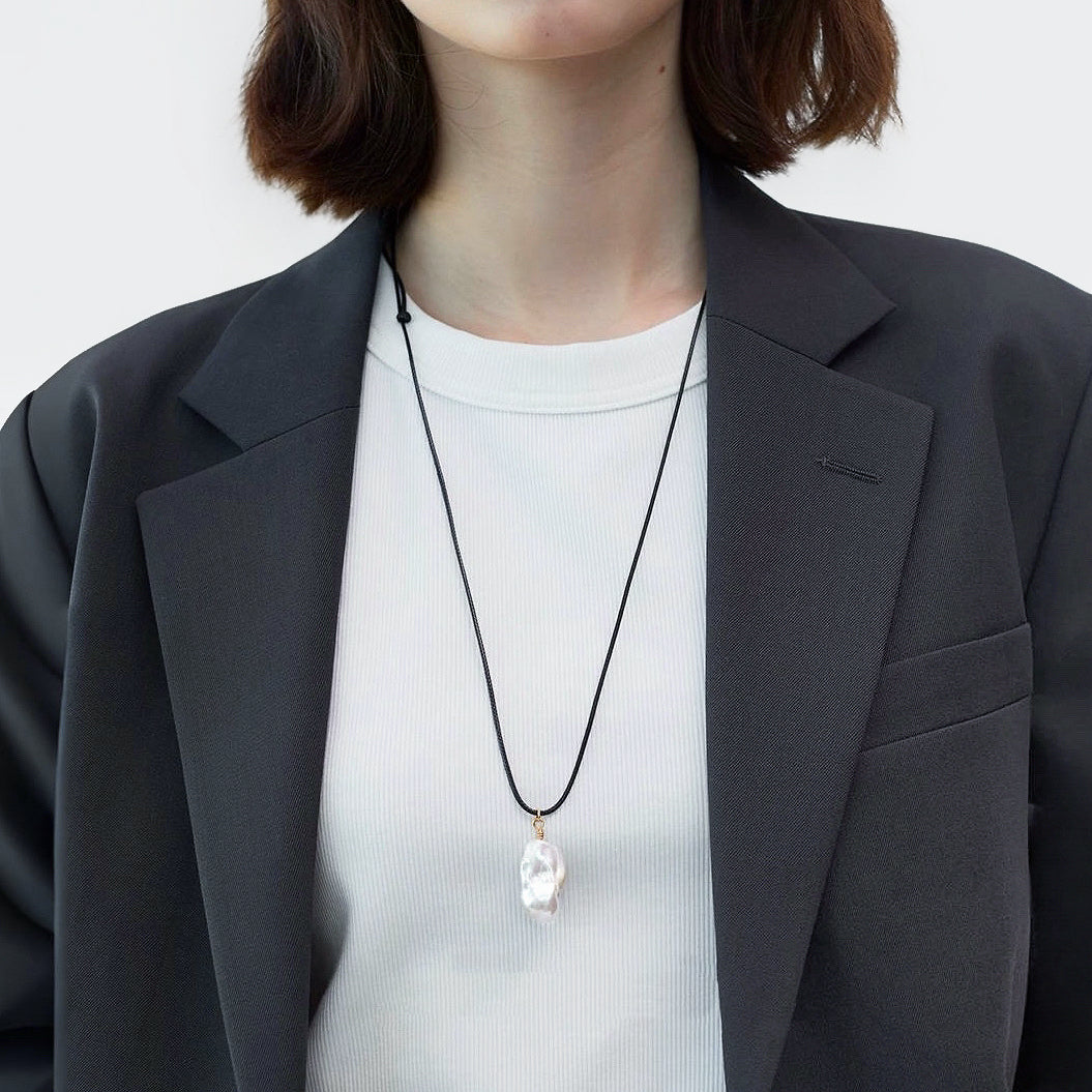 Model wearing silver lustrous drop pendant necklace, minimalist elegant jewelry style