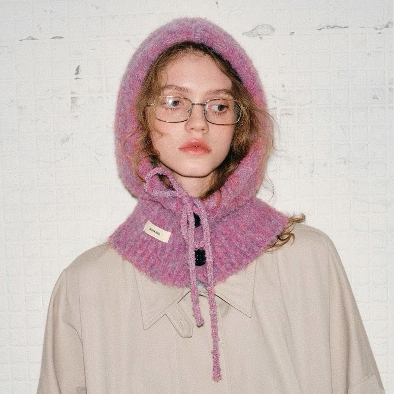 A model wearing a mauve pink buttoned balaclava hat with an adjustable drawstring tie.