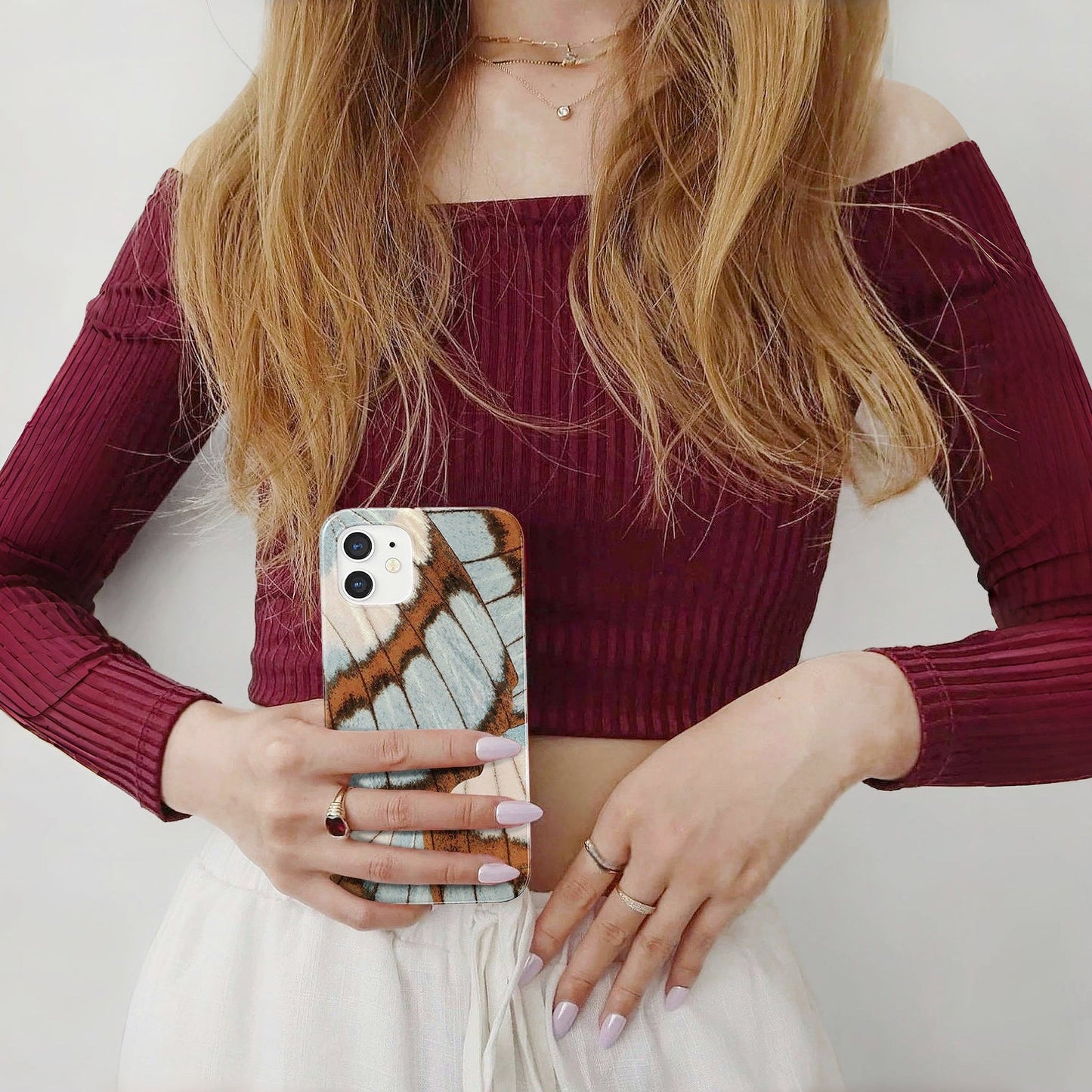 Held by a person, Morpho Flair acrylic case with shimmering butterfly wing motifs. Elegant artistic style.