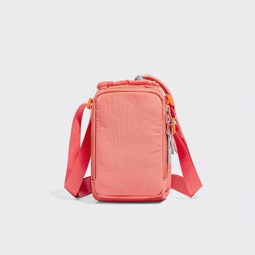 Studio flat lay of the vibrant coral pink multi-way utility bottle bag showcasing its flexible top drawstring closure.