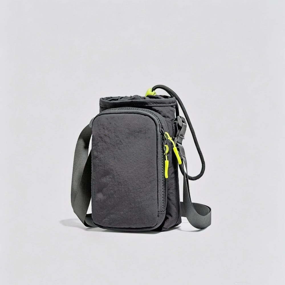 Studio flat lay of the dark grey multi-way nylon bottle carrier featuring its front zippered phone compartment.