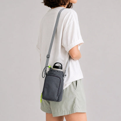 Back view of a model showcasing how the dark grey nylon bottle sling bag sits comfortably flat against the lower back.