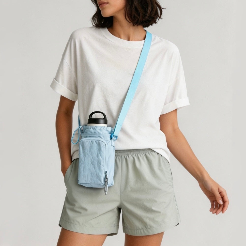 Model styling the light pastel blue nylon water bottle carrier bag over the shoulder with a basic white tee.