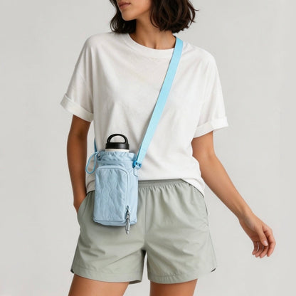Model styling the light pastel blue nylon water bottle carrier bag over the shoulder with a basic white tee.