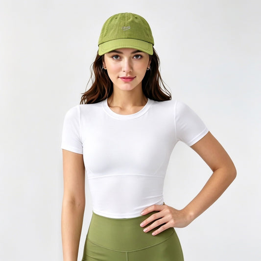 Model styling an olive green quick dry cap for a functional gorpcore outfit with an athletic top.