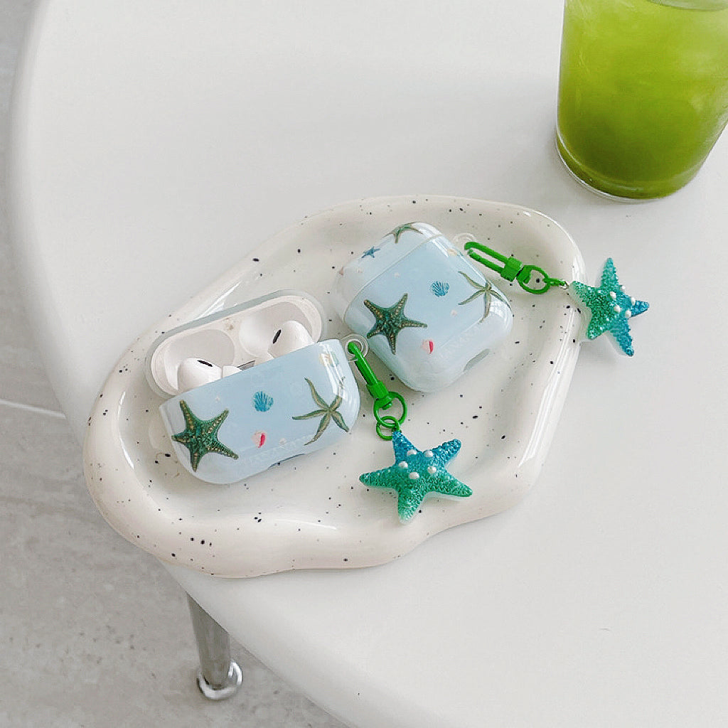 Angled view of two Oceanic Star Charm Airpods Case Cover, easy to carry for commutes and errands.