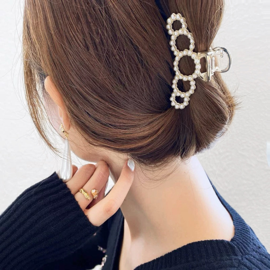 Side view of model styling a medium pearl clip; professional office chic hair accessory for daily use.