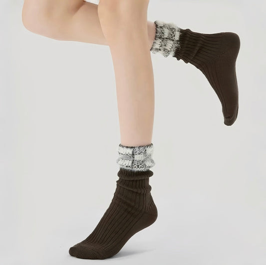 Model wearing a pair of Brown ribbed fuzzy socks with a white and gray plaid cuff.