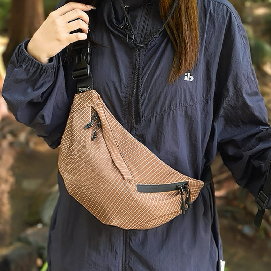Model carrying a brown plaid nylon sling bag as crossbody, great for daily carry and travel.
