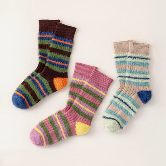 Front view of Three pairs of plush striped socks in brown, purple, and khaki with colorful fuzzy stripes.