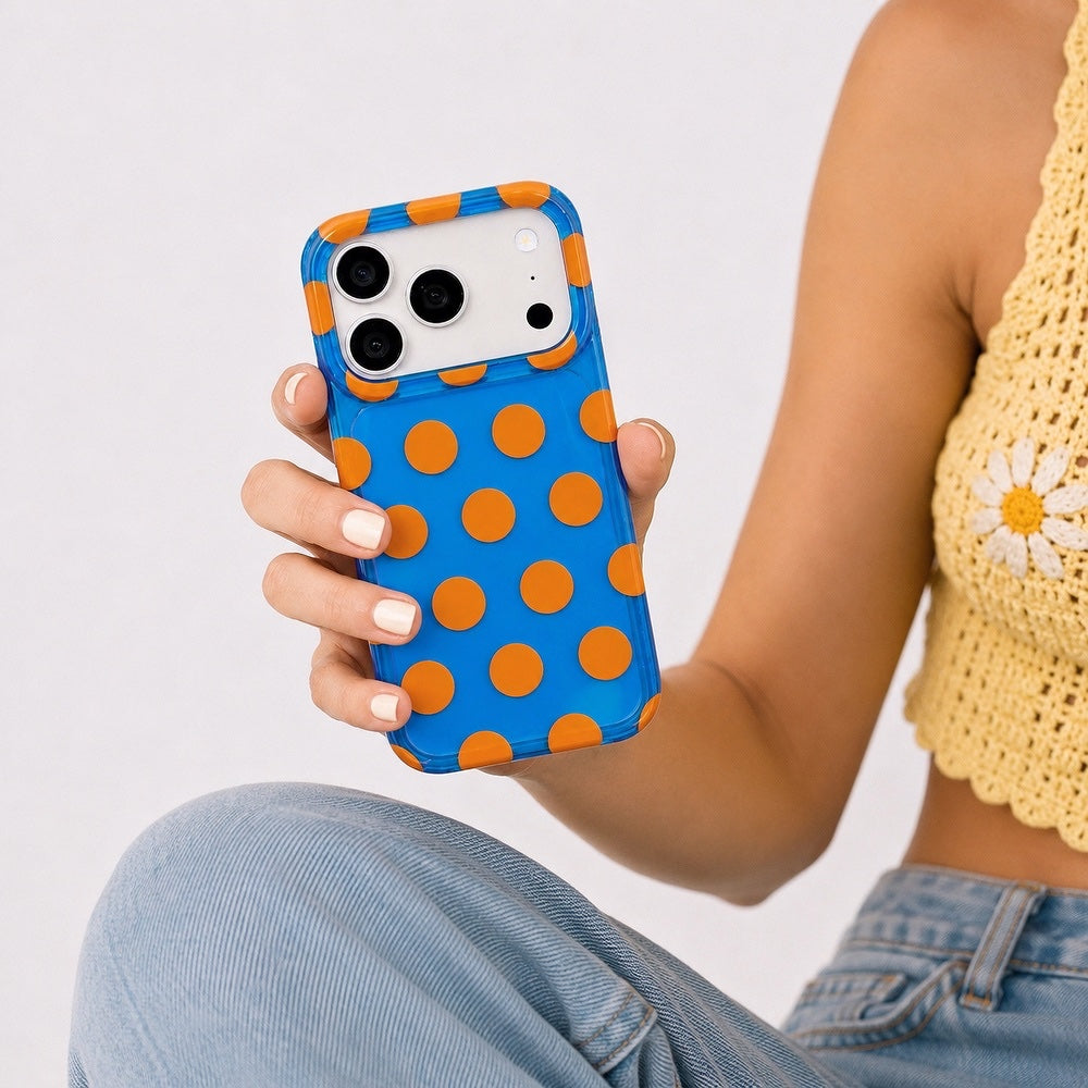 Close-up of a model holding the blue silicone case with orange polka dots.