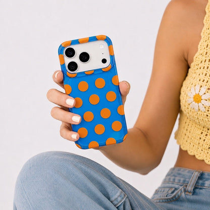 Close-up of a model holding the blue silicone case with orange polka dots.
