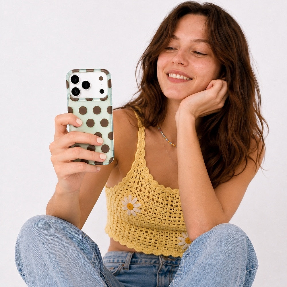 Lifestyle shot of a model holding the mint  silicone phone cover with brown dots.