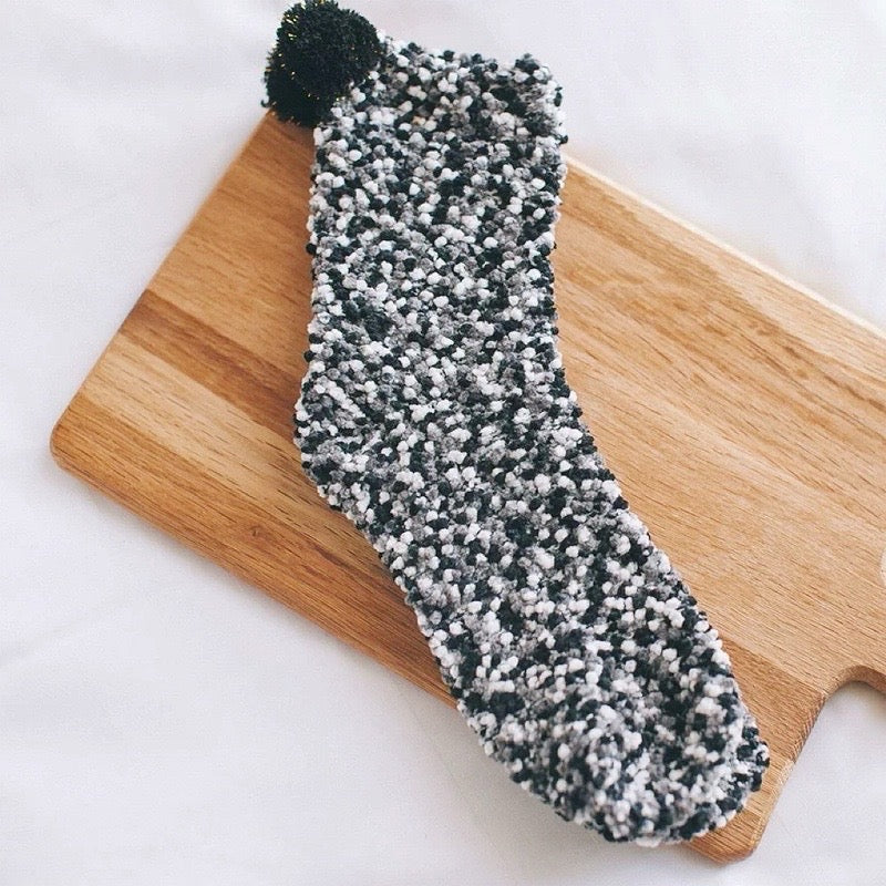 Angled view of Pompom Cupcake Socks in black, easy to pack for travel and errands.