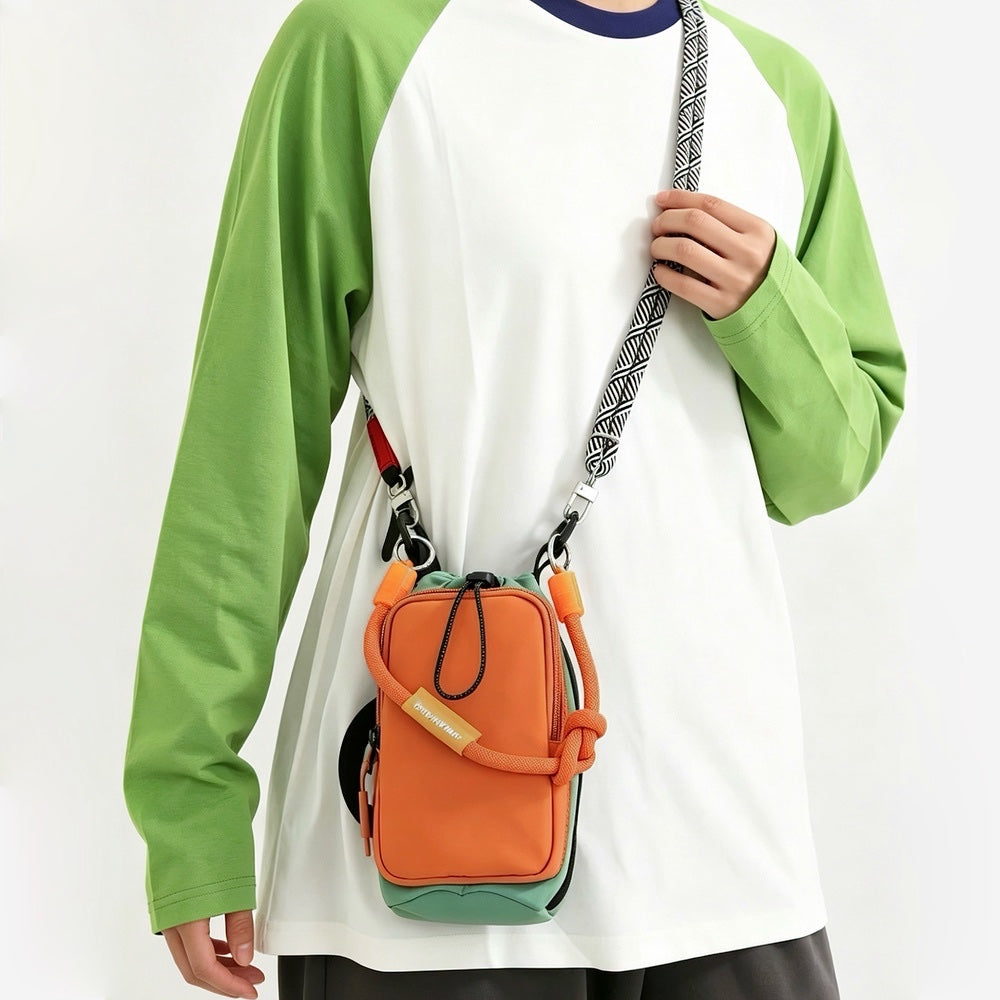 Model wearing a green-sleeved raglan shirt styling the vibrant orange utility bottle carrier bag over the shoulder.