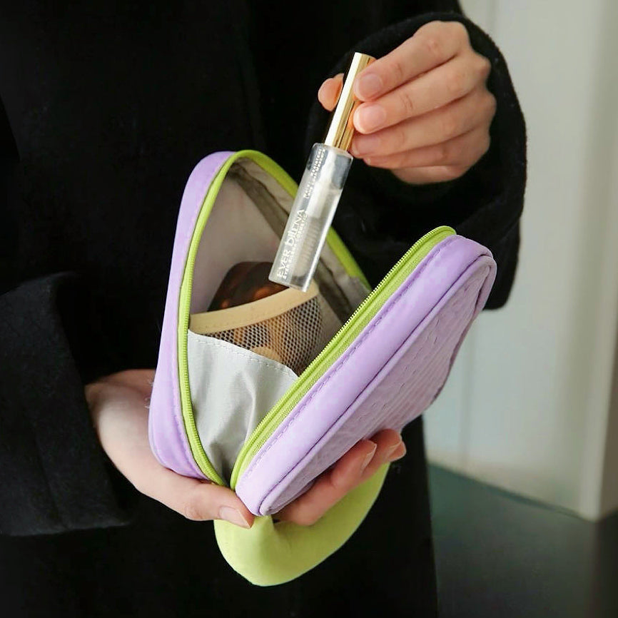 Hands holding open purple Puffy Candy triangle mini bag; quilted zip organizer with mesh pocket for makeup.