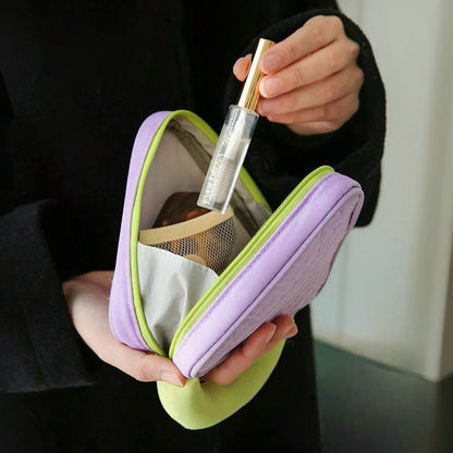 Hands holding open purple Puffy Candy triangle mini bag; quilted zip organizer with mesh pocket for makeup.