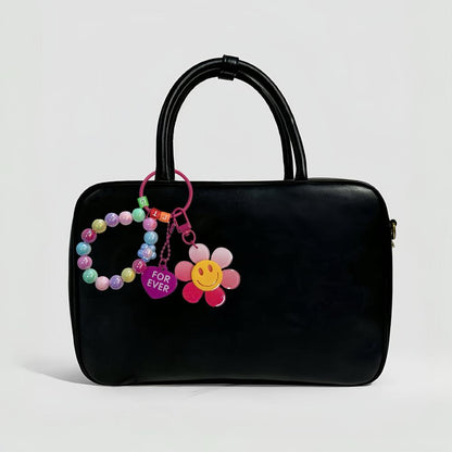 Rainbow Beads Sunflower Bag Charm hanging on a black bag, easy for gifting and photo-ready styling.