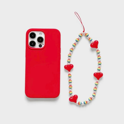 Red silicone case with a rainbow heart charm made of acrylic beads. Playful handcrafted jewelry style.