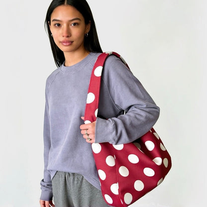 Model wearing a red suede hobo bag with white polka dots for a modern casual look.