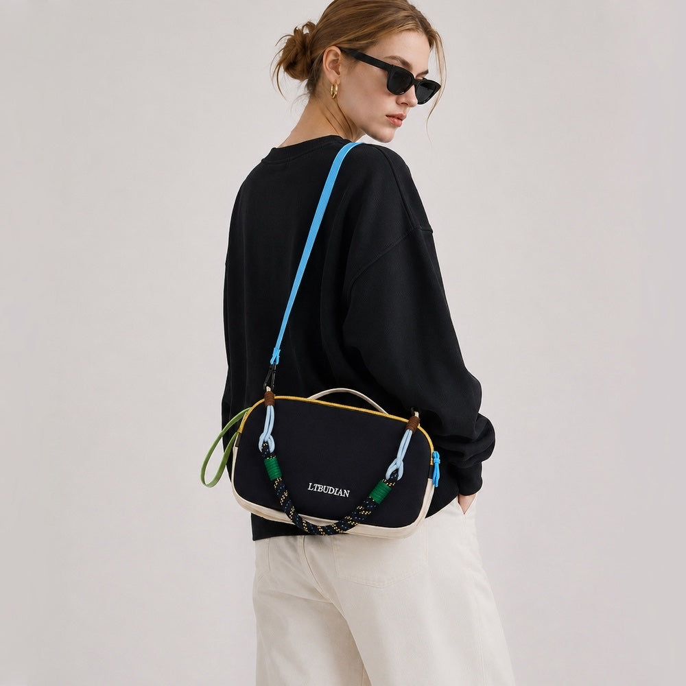 Model wearing the navy blue reversed side of the colorblock utility bag over a black sweater.