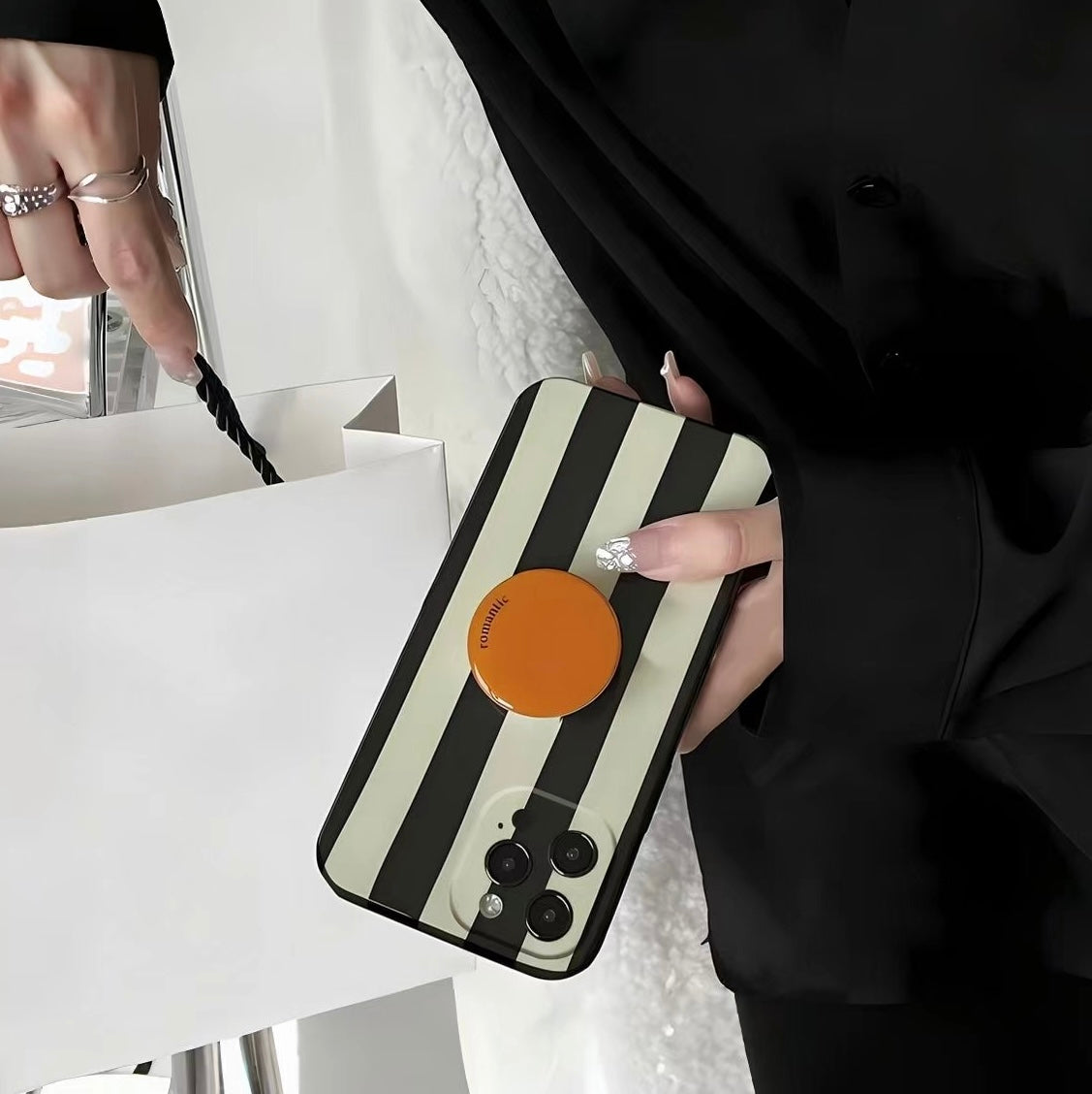 Handheld stripe phone case with grip; stylish accessory perfect for mirror selfies and social media content.