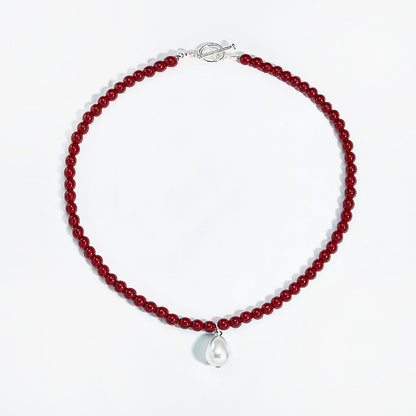 Flat lay of red rose dew necklace showing artificial pearl drop and toggle clasp