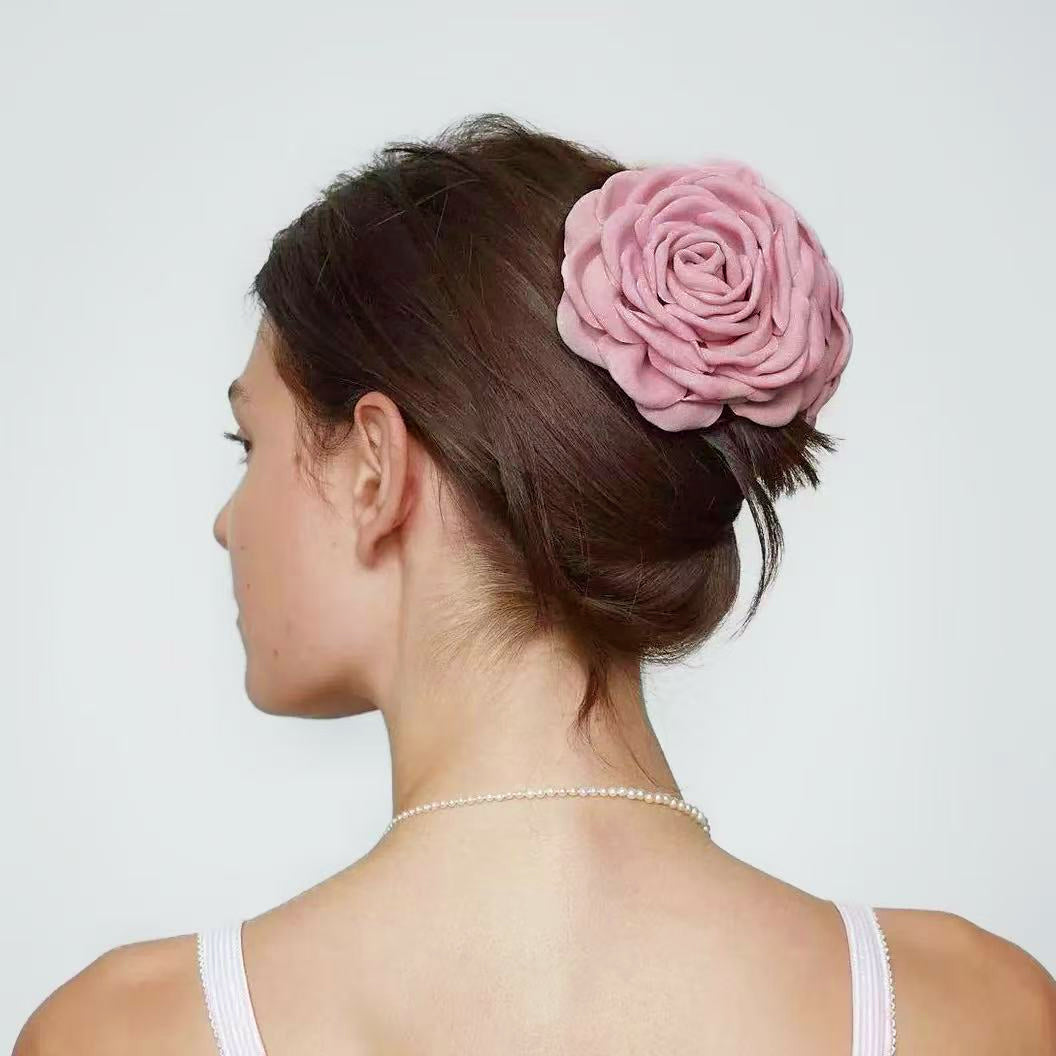 Back view of a model with an elegant updo secured by a dusty pink rose hair claw.