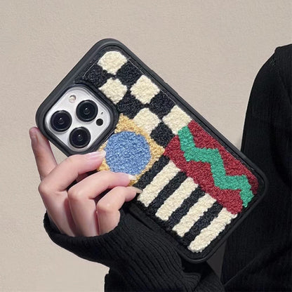 Model holding the sherpa fleece phone case, showcasing the artistic geometric embroidered design.