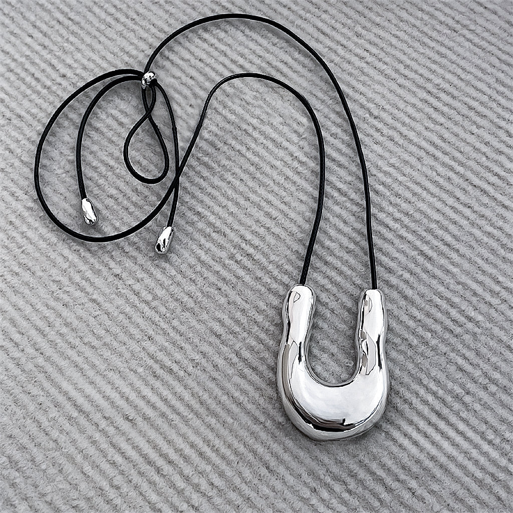 Flat lay of Silver Crescent Pendant Necklace, great for everyday outfits.