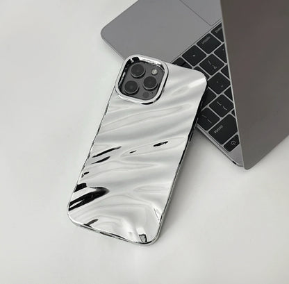 Silver glossy wave case with a reflective fluid design, shown next to a laptop.