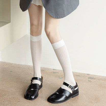Model wearing a pair of white striped split-toe socks in knee-high lengths, easy for travel days and daily comfort.