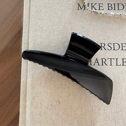Flat lay of Sleek Curved Hair Claw  in black, easy for workdays and special occasions.