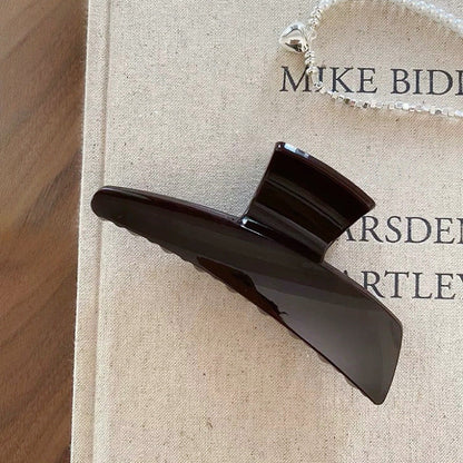 Flat lay of Sleek Curved Hair Claw  in dark brown, great for everyday styling and gifting.