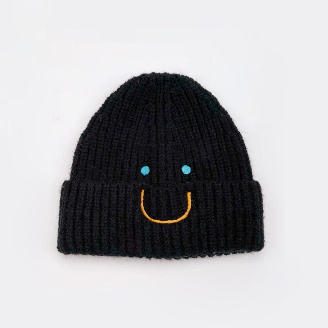 Front view of Smiley Ribbed Knit Beanie in black. Minimalist dark tone paired with a playful smile motif.