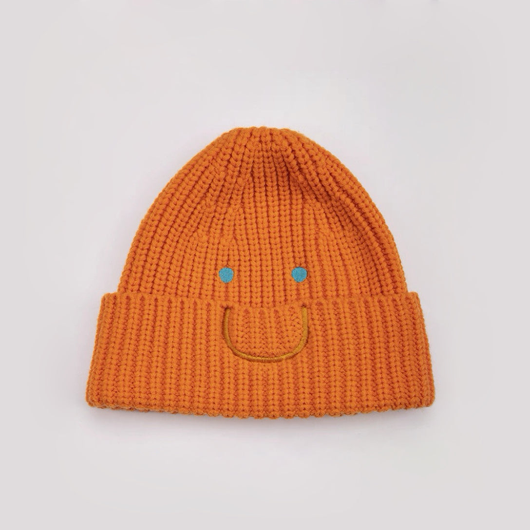Front view of Smiley Ribbed Knit Beanie in orange. Vibrant fall color with a whimsical smile embroidery.