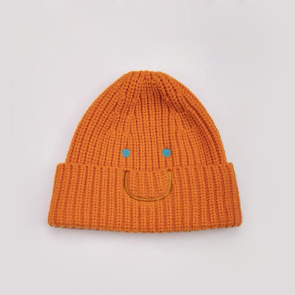 Front view of Smiley Ribbed Knit Beanie in orange. Vibrant fall color with a whimsical smile embroidery.