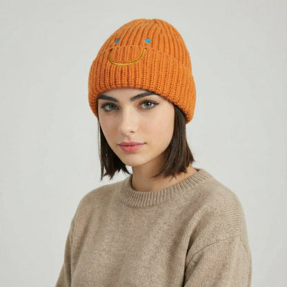 Model wearing Smiley Ribbed Knit Beanie in orange. Warm and soft ribbed knit for cold-weather comfort.