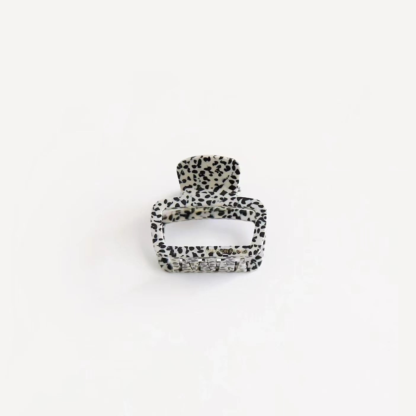 Black and white dots print square hair clip on clean background, trendy graphic pattern for street style accents.