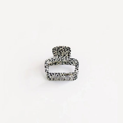 Black and white dots print square hair clip on clean background, trendy graphic pattern for street style accents.