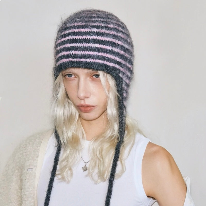 Front view of a model wearing the pink and dark grey striped earflap hat for a cozy look.