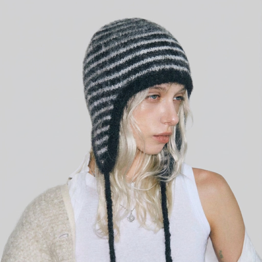 Side view of model wearing the classic black and white striped earflap hat.