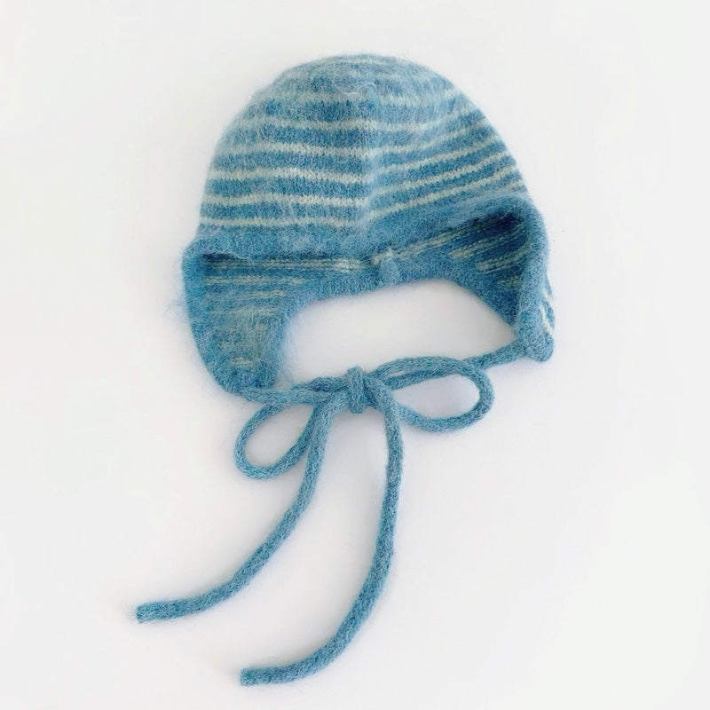 Blue and white striped knit earflap hat with braided tassel ties on white background.